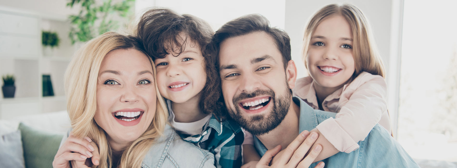 A family photo with a smiling woman, man, and child in front of a blurred background, all posing for the camera.